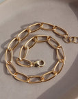 14k gold fill Curve Bracelet sitting on the peach colored plate. Handmade in Eau Claire Wisconsin.