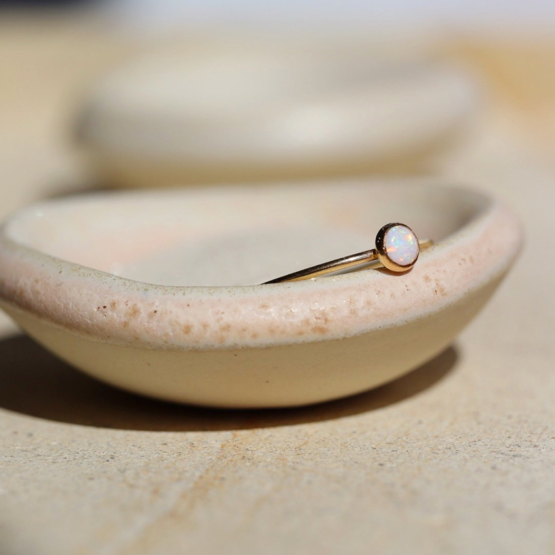14k gold fill Opal ring placed on a ring dish in the sunlight.