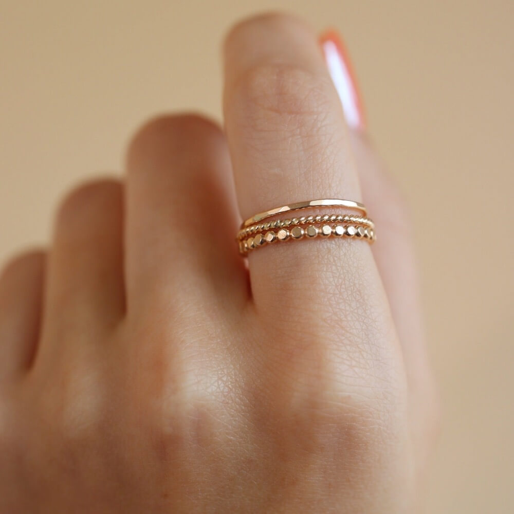 Model wearing 14k gold fill SoHo Ring Set on the middle finger. This Ring set highlights each one of our go to stacking rings including the stacking ring, spiral ring, and sequins ring. These rings are made to live in made to wear everyday.
