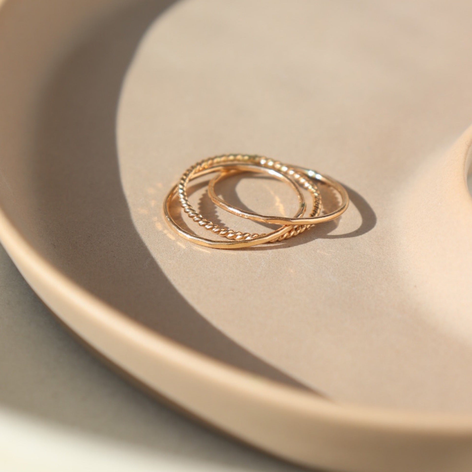 14k gold fill Tribeca Ring laid on a tan plate in the sunlight. This ring features a super cute laid look but its one ring.