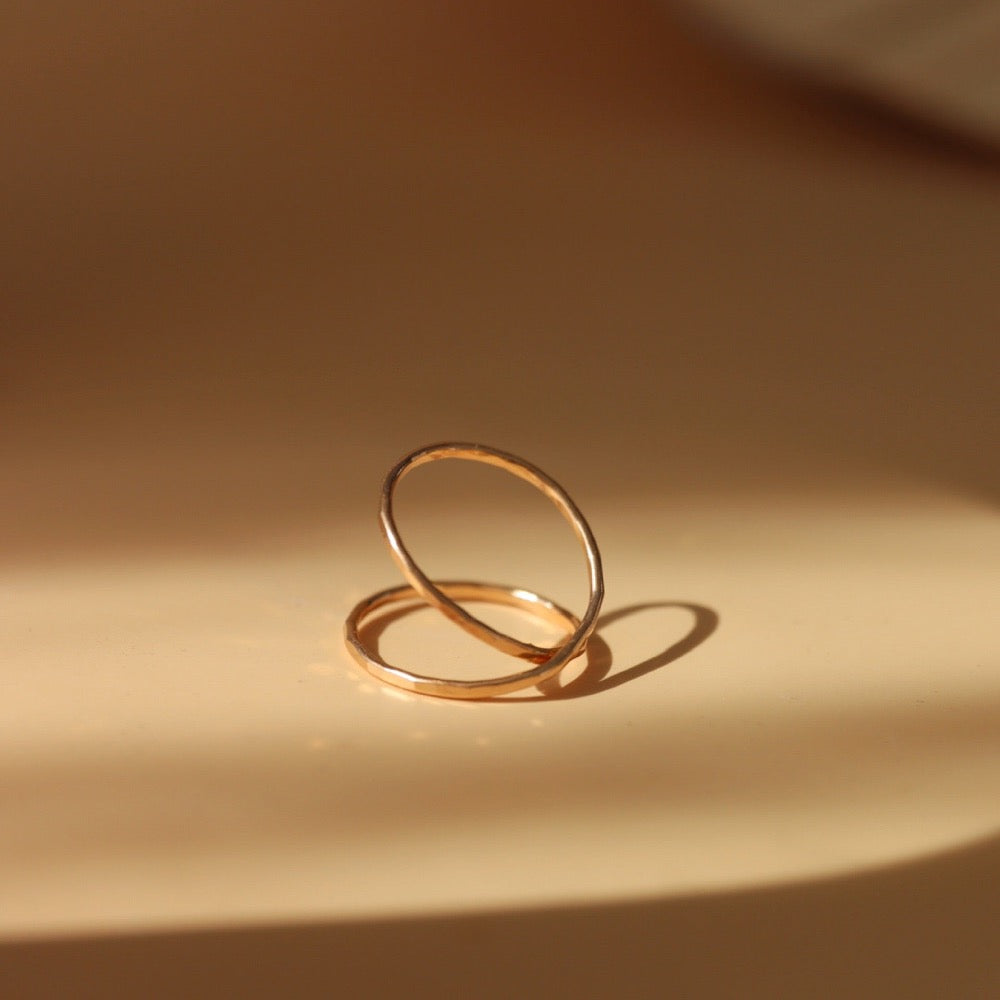 14k gold fill infinity ring laid on a tan plate.