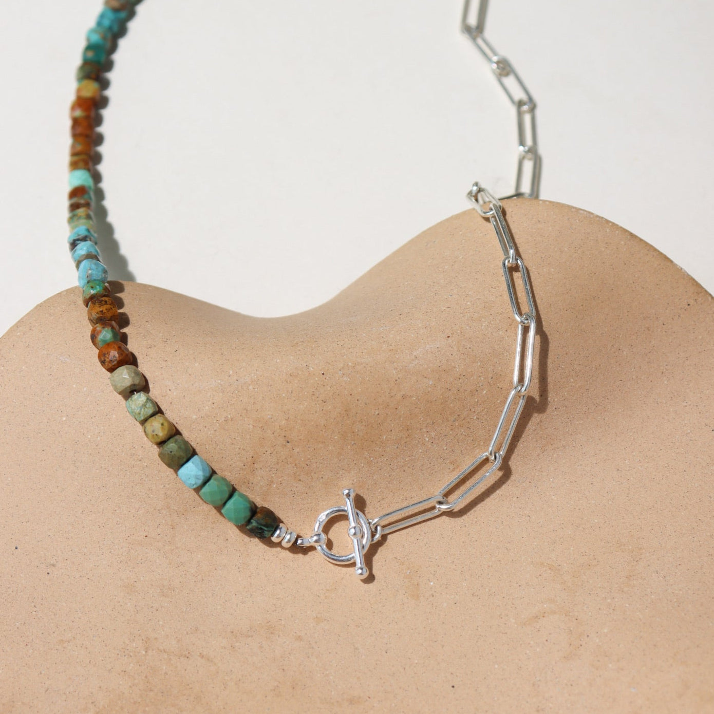 Taos Toggle Necklace featuring half turquoise beads and half silver paperclip chain with a front toggle clasp displayed against a cream back drop