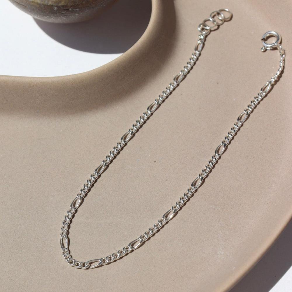 925 sterling silver Capri Bracelet laid on a tan plate in the sunlight.