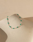 sterling silver chain bracelet with transparent emerald gemstones on a light dish