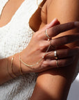 Model wearing 14k gold fill hand chain with pearls paired with other 14k gold fill jewelry