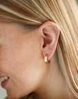 Model wearing the small pair of mirage hoops, featuring a thick hammered wire.