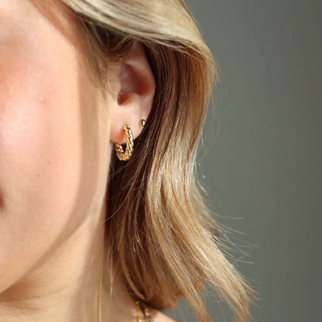 Model wearing Croissant Huggie Hoops, worn with the classic studs.