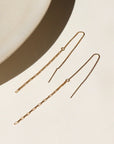 14k gold fill threader earring, displayed on a cream backdrop in the sunlight