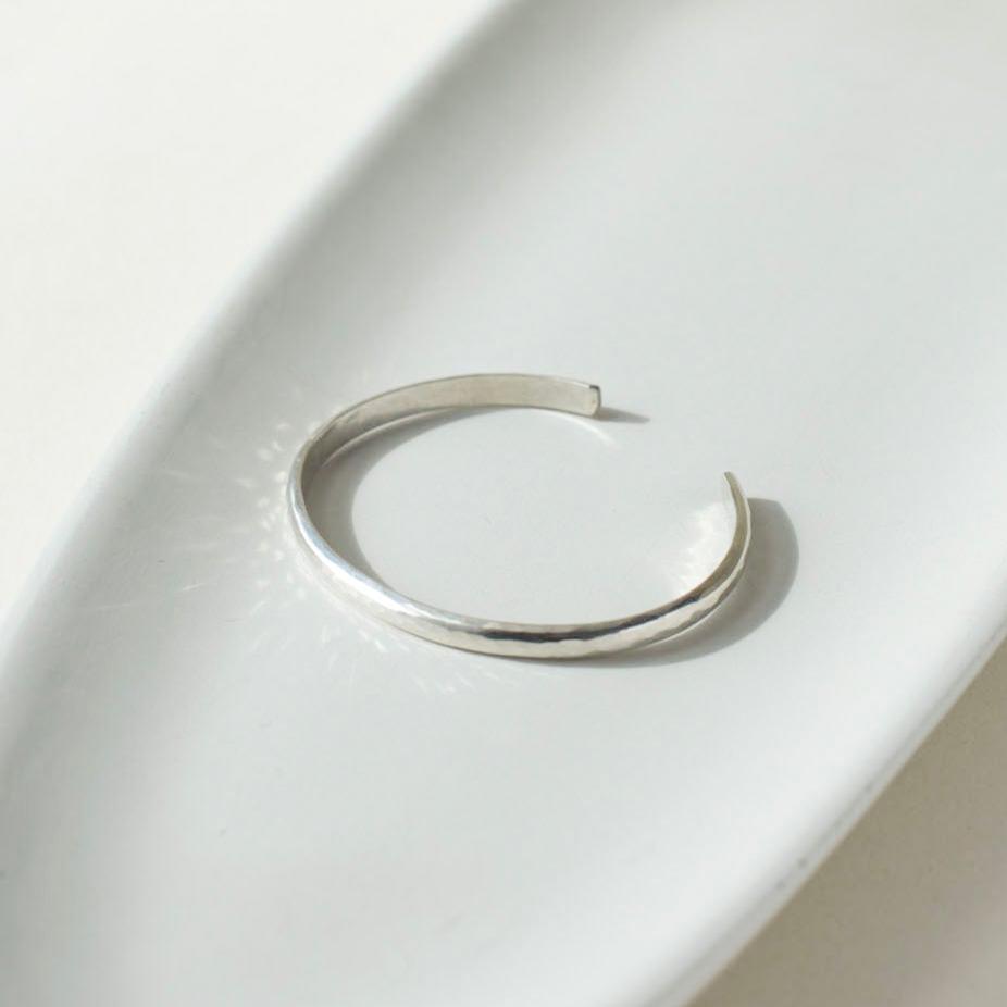 925 stacking cuff placed on a light gray plate, set in the sunlight.