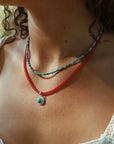 model wearing turquoise and ruby beaded necklaces with round turquoise pendant