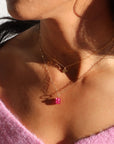 model wearing pink topaz charm in 14k gold fill on heart chain necklace layered with a heart charm necklace in 14k gold fill