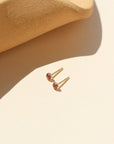 A 3mm pink tourmaline gemstone set into a 14k gold fill stud, displayed in the sunlight.