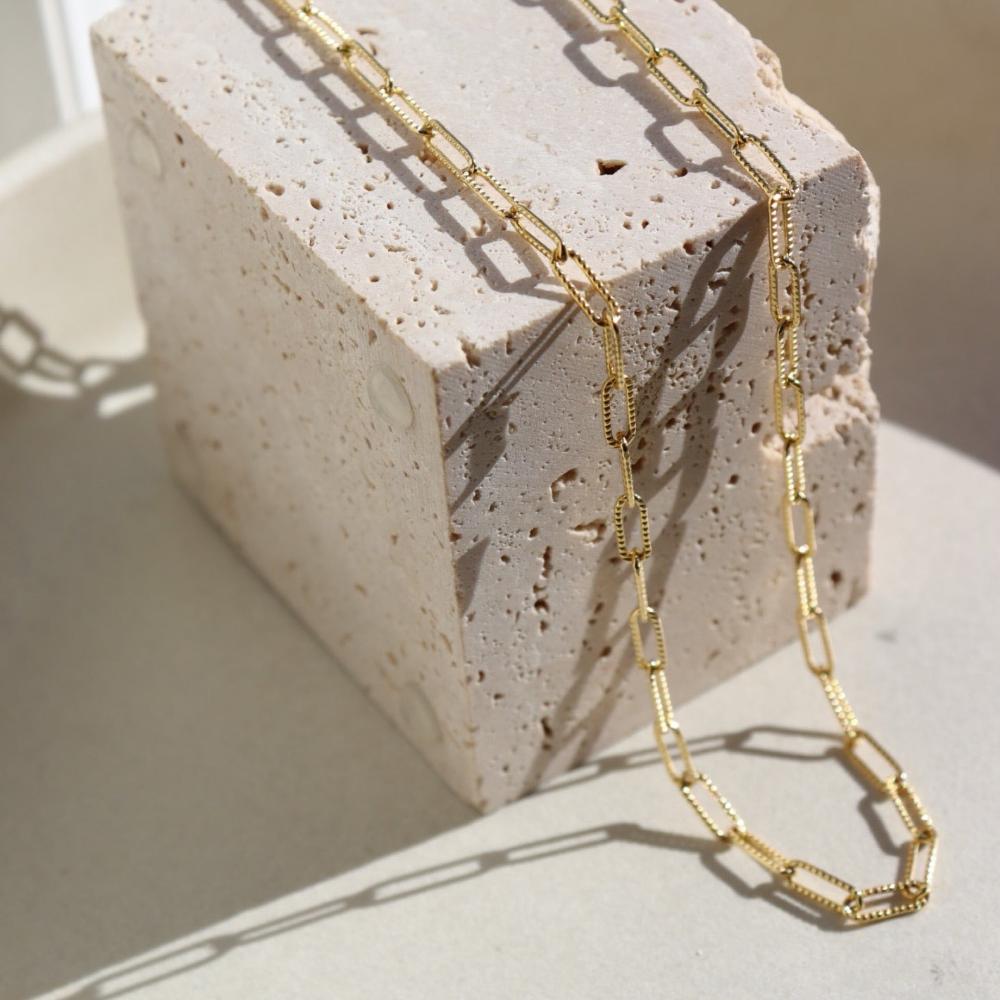 14k gold fill Piper necklace laid on a stone plate in the sunlight.
