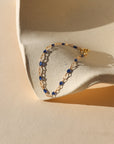 14k gold fill chain with transparent sapphire enamel as a bracelet on a light dish