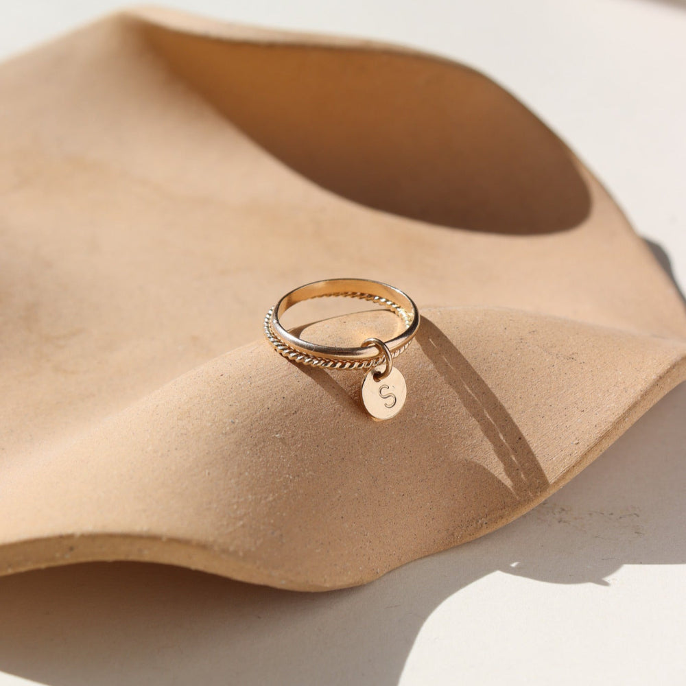 A smooth band stacked with a spiral 14k gold fill band, with a small "S" stamped disc attached to both rings.