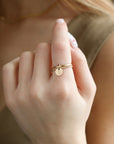 Model wearing a smooth band stacked with a spiral 14k gold fill band, with a small "S" stamped disc attached to both rings.