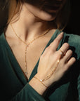 Gold sunburst hand chain featuring delicate textured links and a raw Herkimer diamond accent.