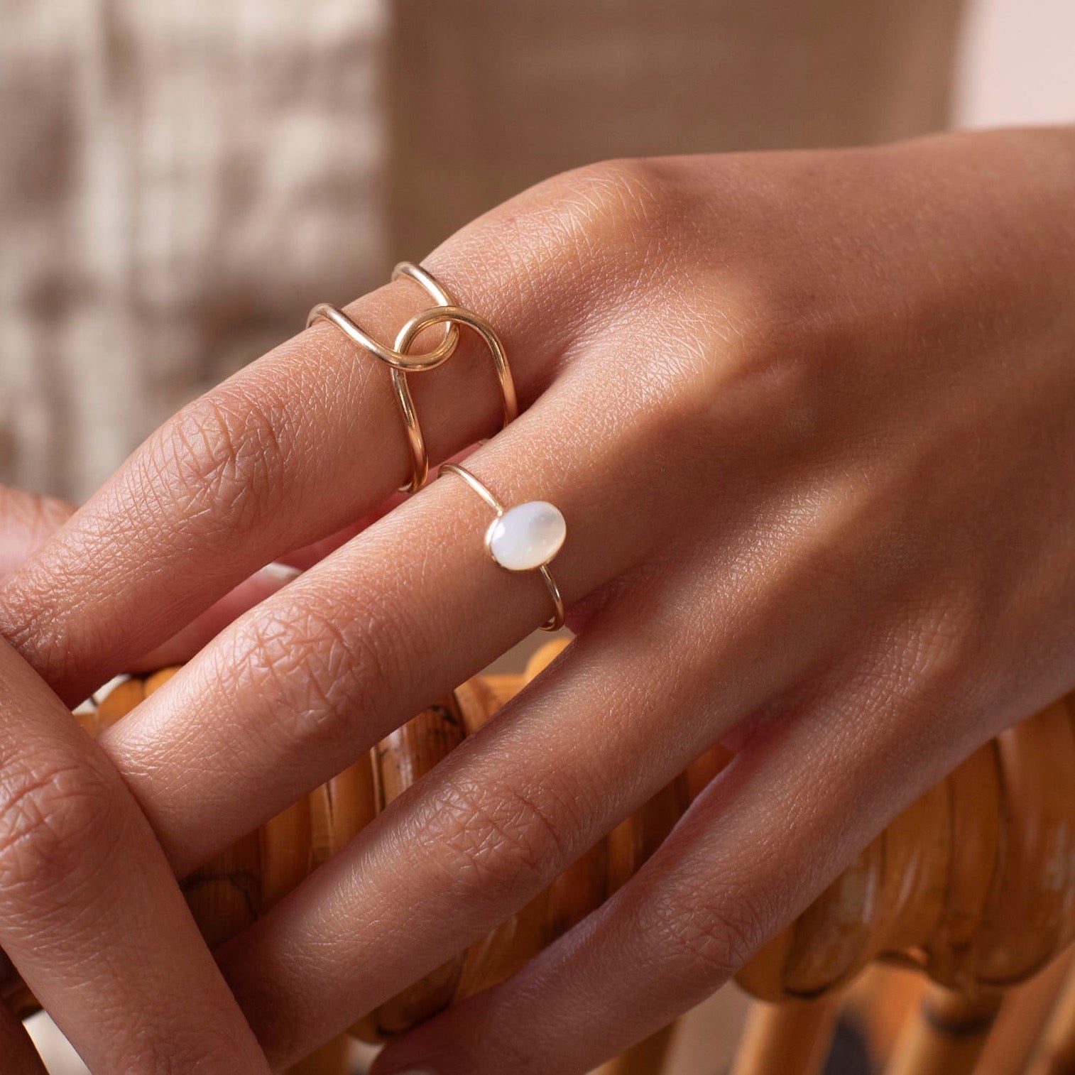 mother of pearl stone set in a bezel on a 14k gold fill skinny ring band, photographed on a model's hand