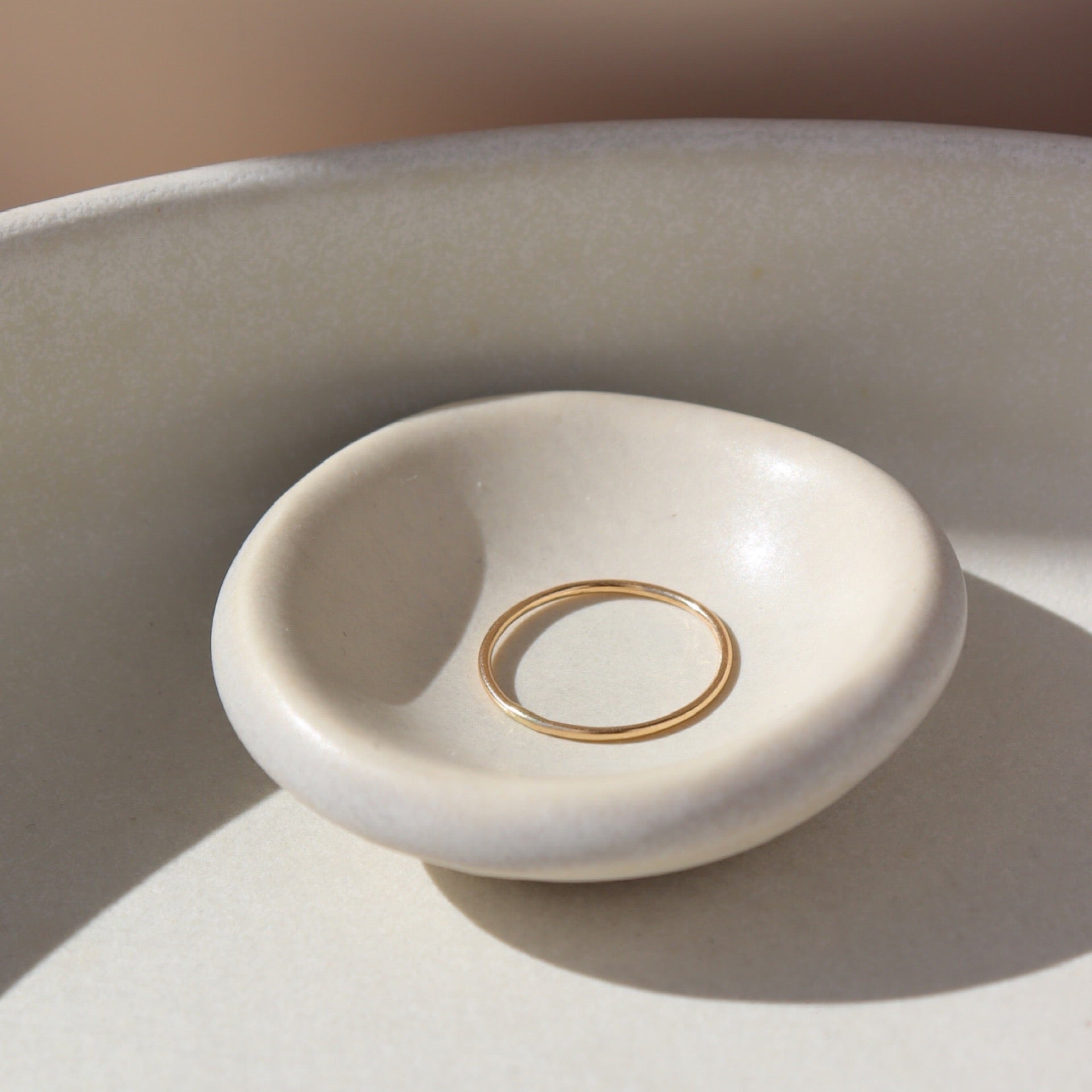 14k gold fill Minimal Ring Laid on a white ring dish. This ring features a simple band that is smooth, great for everyday wear.