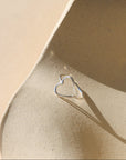 Silver heart-shaped ring on a beige ceramic surface