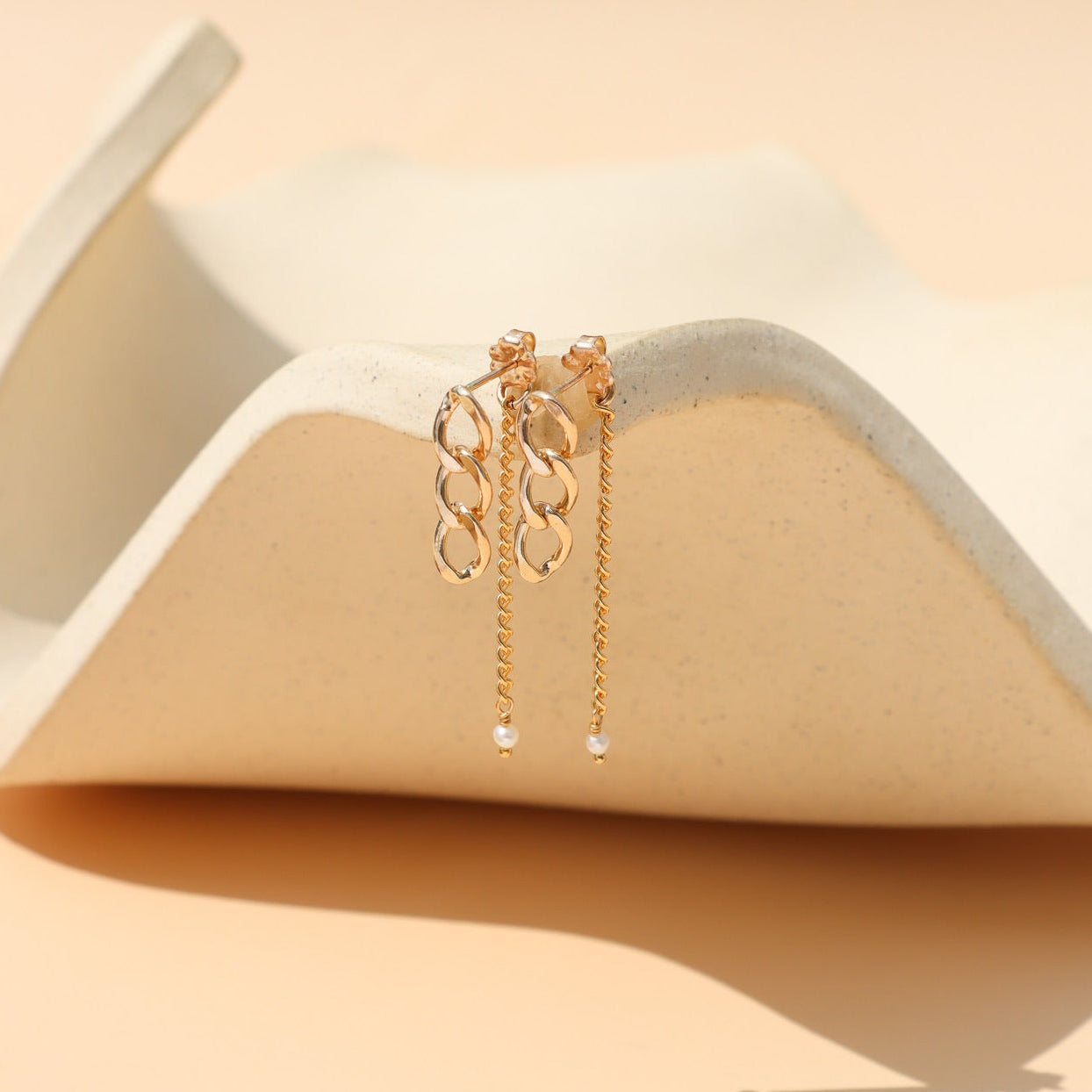 Gold stud earrings with freshwater pearls, chain link details, and a modern minimalist design, featuring the Alex Pearl Stud Earrings displayed in warm natural light.