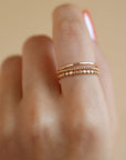 Model wearing 14k gold fill SoHo Ring Set on the middle finger. This Ring set highlights each one of our go to stacking rings including the stacking ring, spiral ring, and sequins ring. These rings are made to live in made to wear everyday. 