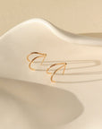 14k gold fill wishbone studs laid on a white plate
