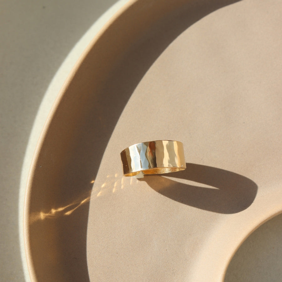 14k gold fill Luxe Ring placed on a tan plate in the sunlight. This ring features Lightly hammered and sophisticated ring cuff.