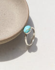 Sterling silver canyon ring with turquoise stone resting on a stoneware dish.