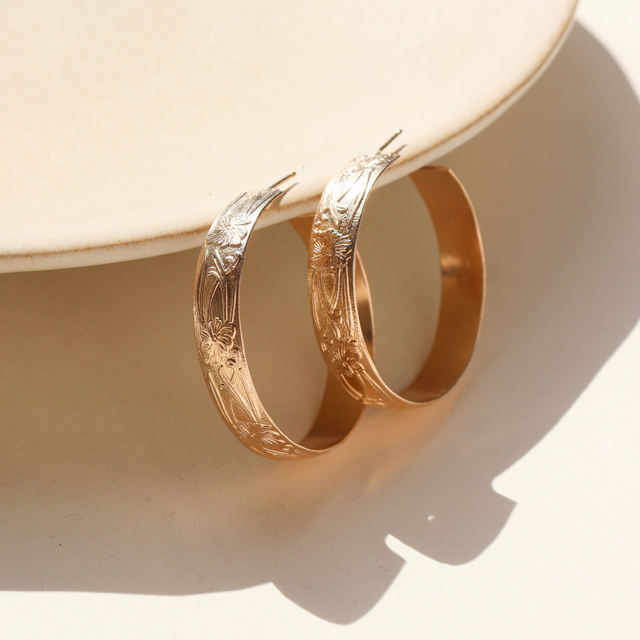 14k gold filled florence hoops resting on a stoneware plate in the sunlight