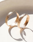 14k gold fill Florence hoops laid on a white plate in the sunlight