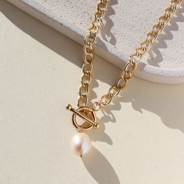 14k gold fill chain with a toggle clasp and large pearl, photographed on a sunlit tabletop