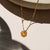Agate donut shaped gemstone pendant attached to a 14k gold Fill chain in the sunlight