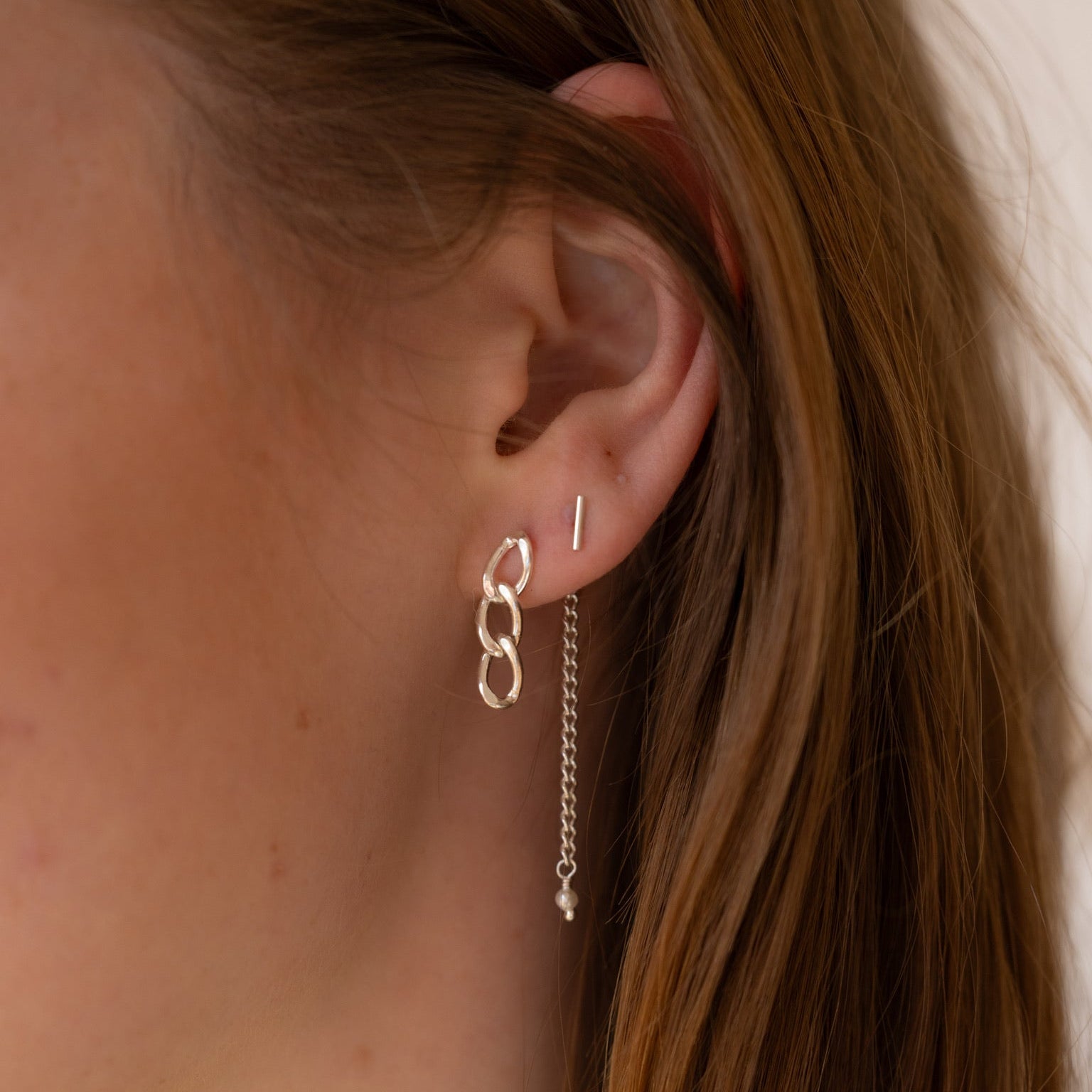 Model wearing sterling silver chain link drop earrings paired with a sterling silver bar stud and delicate chain threader earring with a freshwater pearl accent. Minimal layered ear stack.