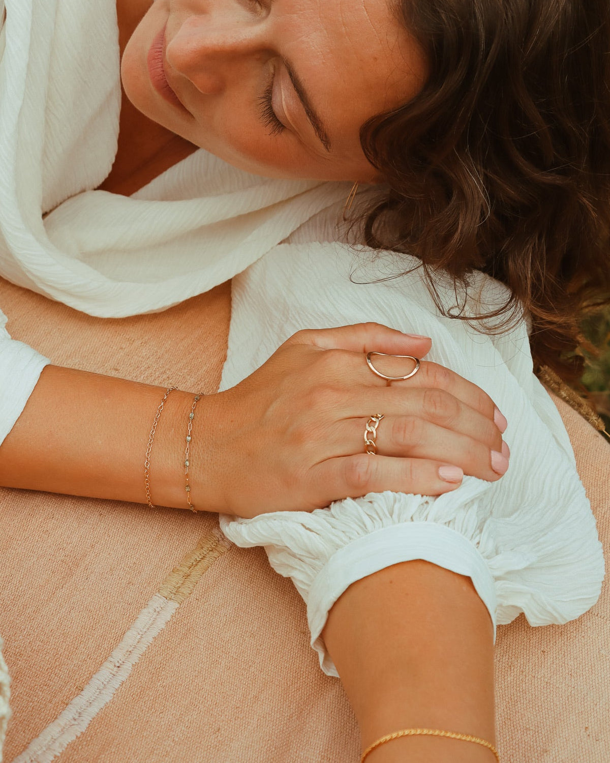 Woman wearing a hammered gold hoop earring with layered gold ear cuffs and delicate chain details.