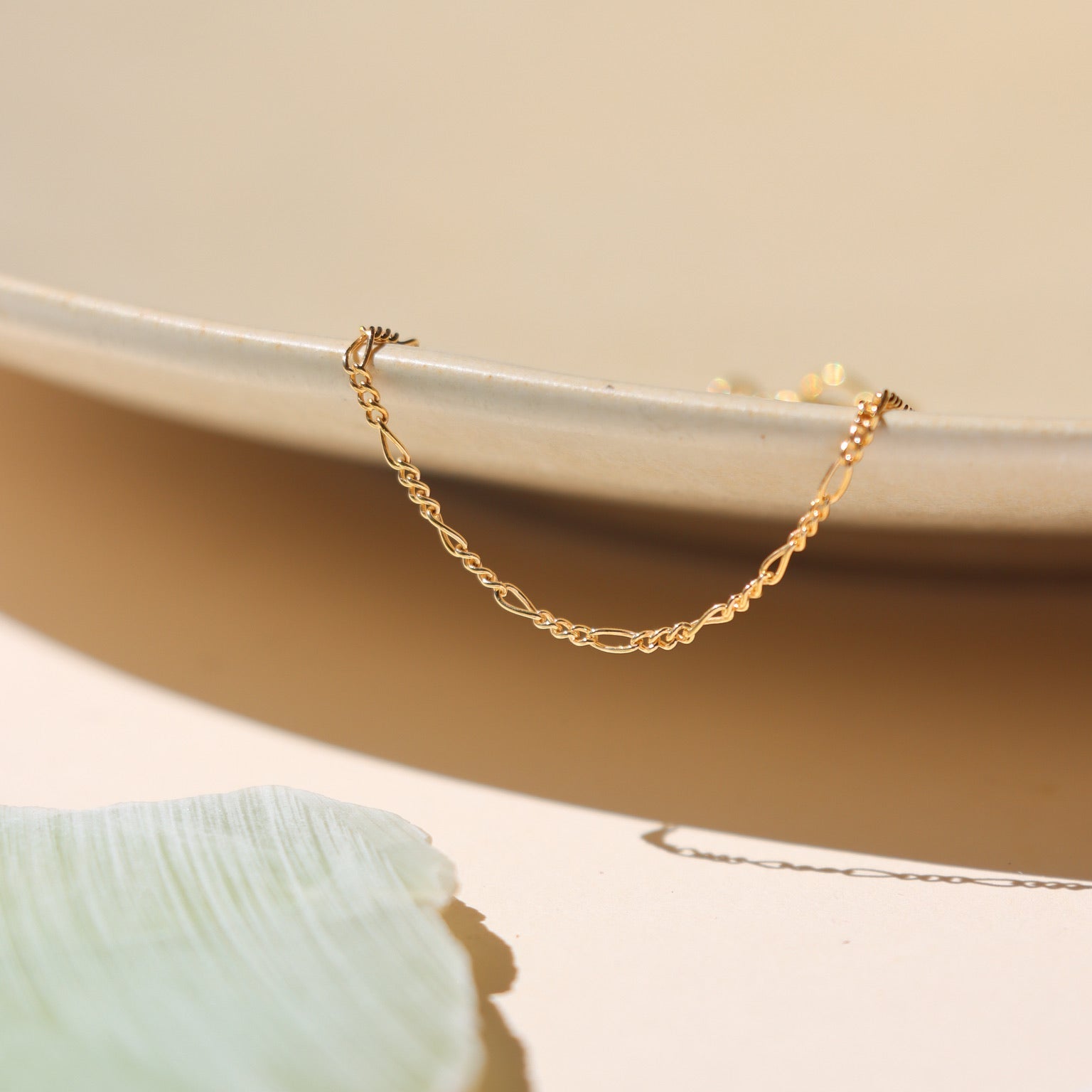 14k gold fill delicate figaro chain anklet on a light dish