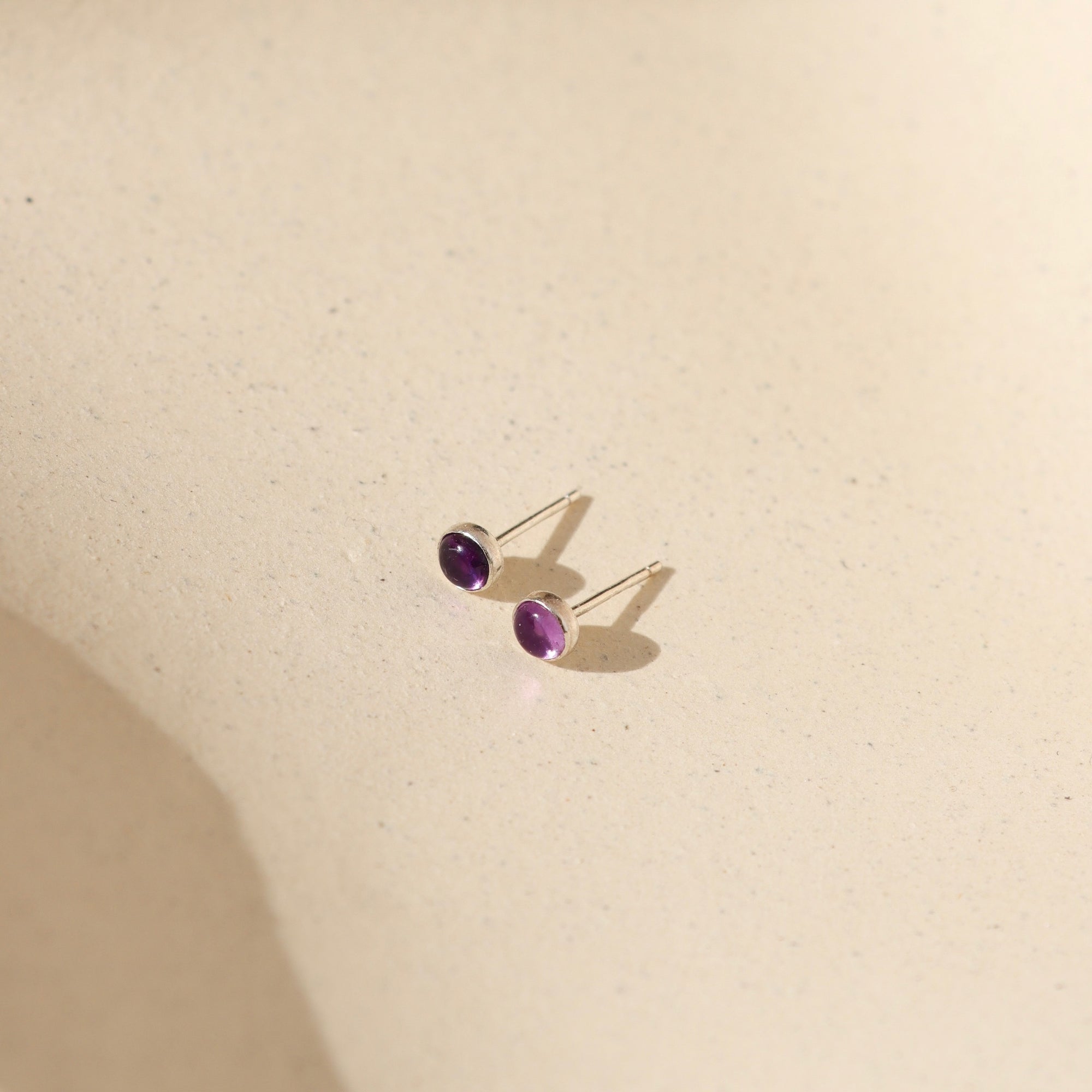 sterling silver bezel studs with amethyst stones on a light background