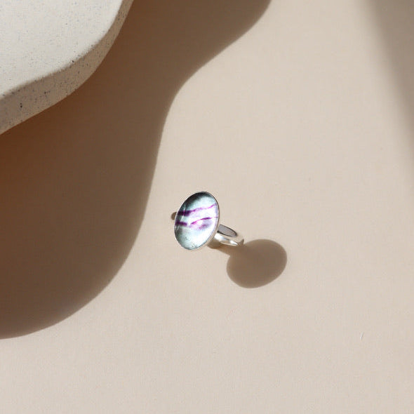 sterling silver ring setting with handset fluorite stone on a light background