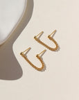 Two gold ball posts connected with a curb chain. 