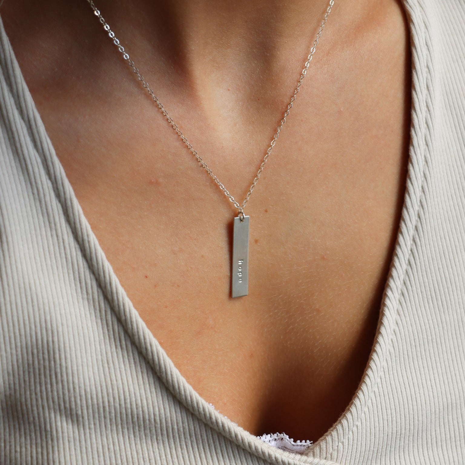 model wearing sterling silver delicate chain necklace with hand crafted sterling silver bar with engraving 