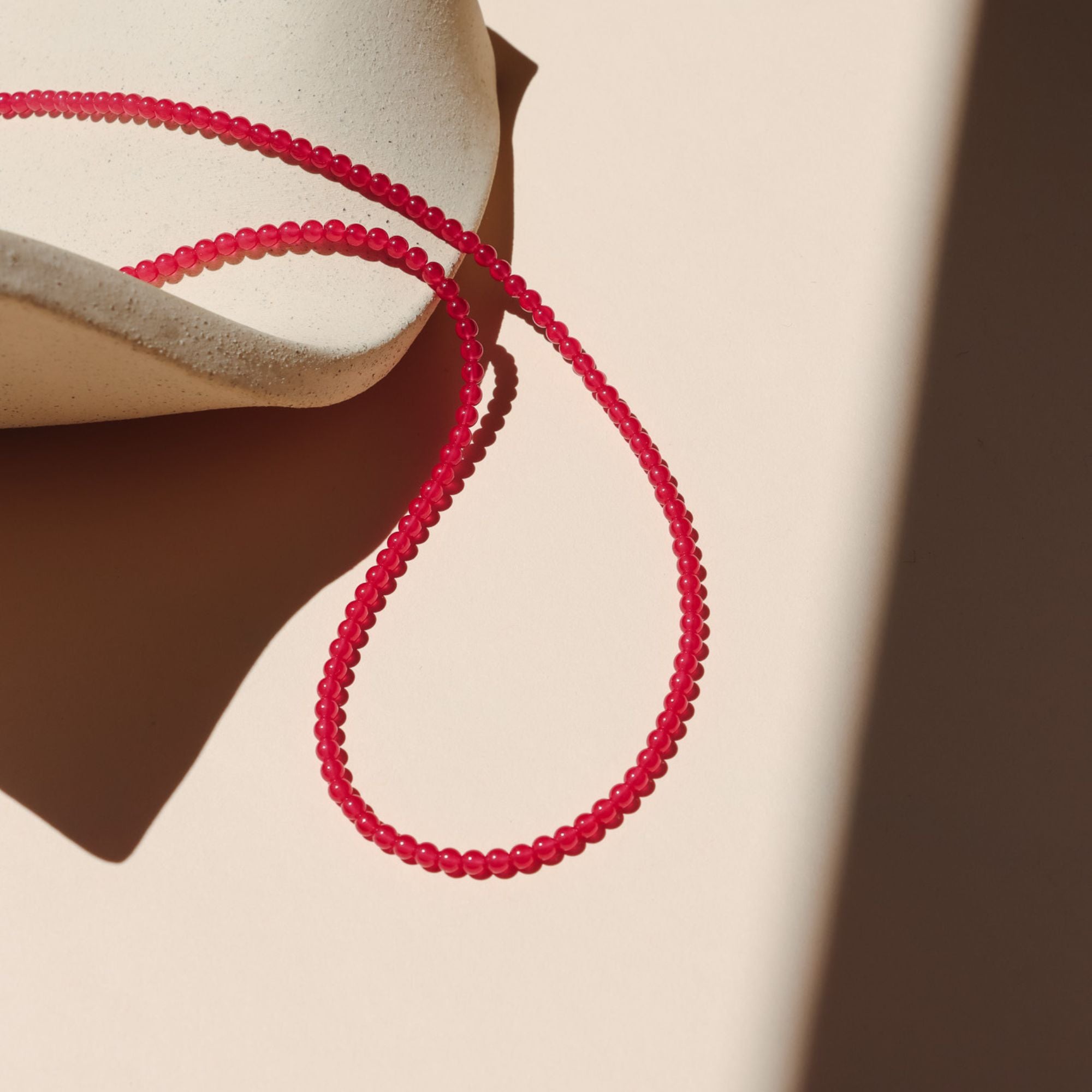 beaded necklace with smooth ruby stones on a light dish