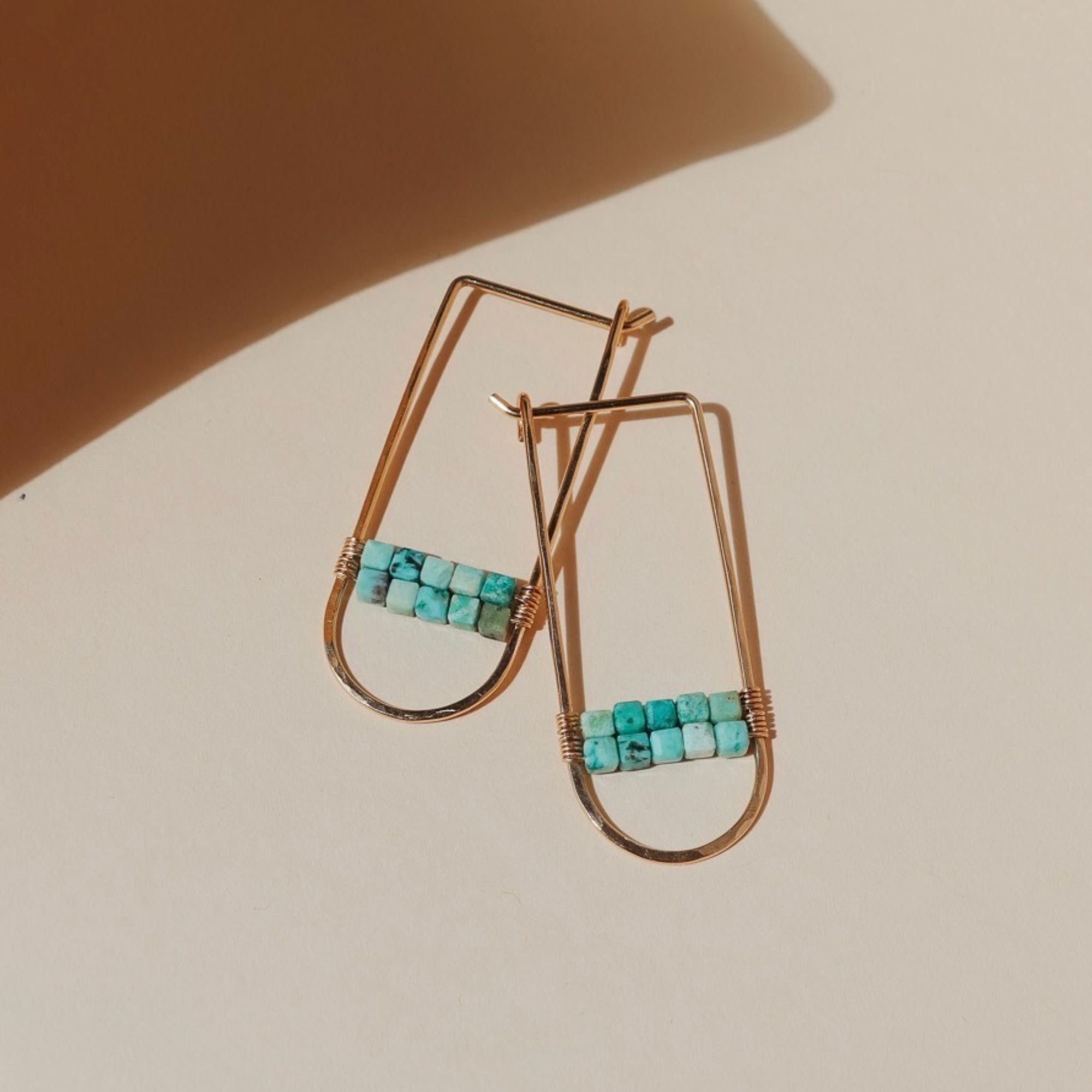 14k gold fill hoops with turquoise stones on a light dish