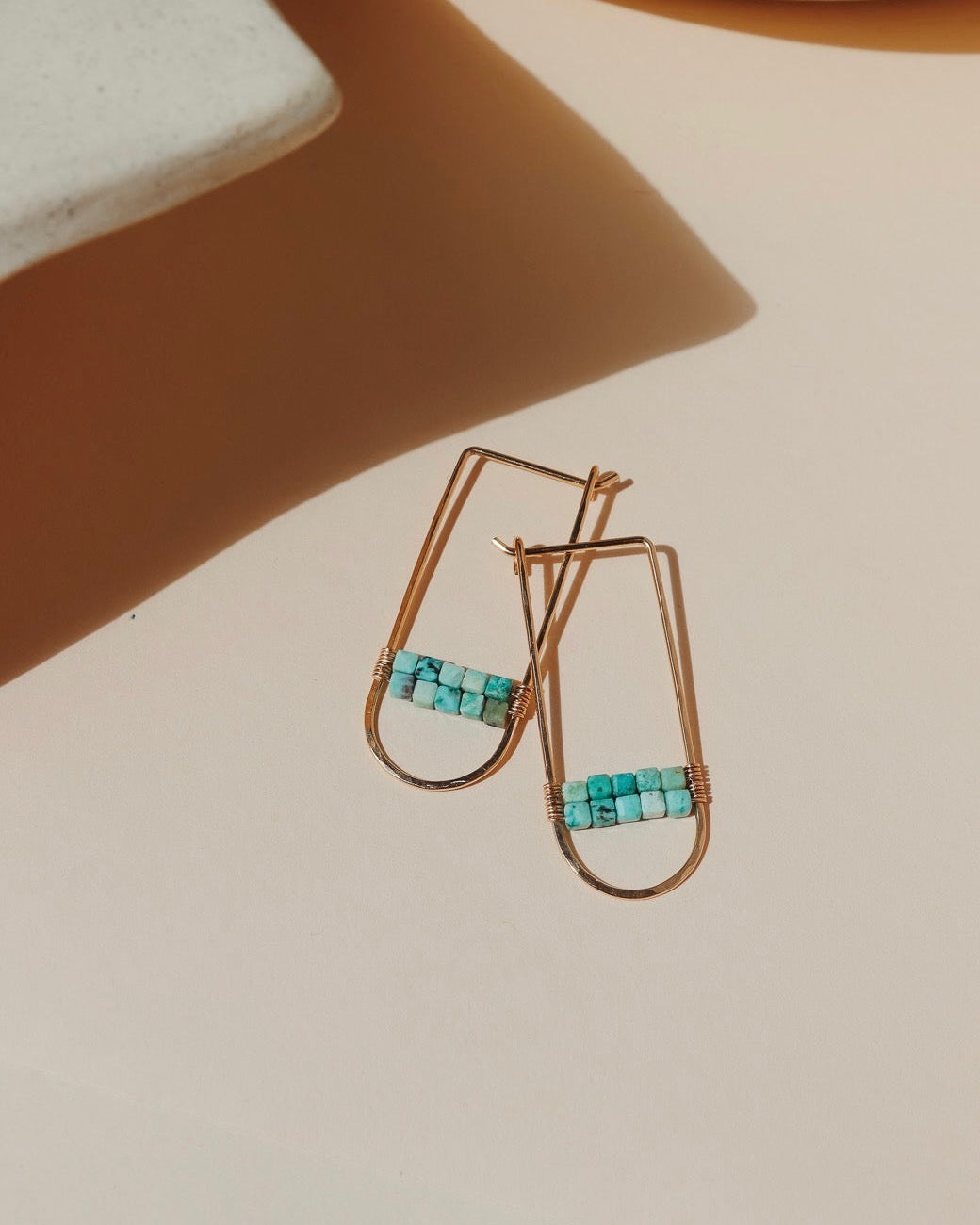14k gold fill hoops with turquoise stones on a light dish