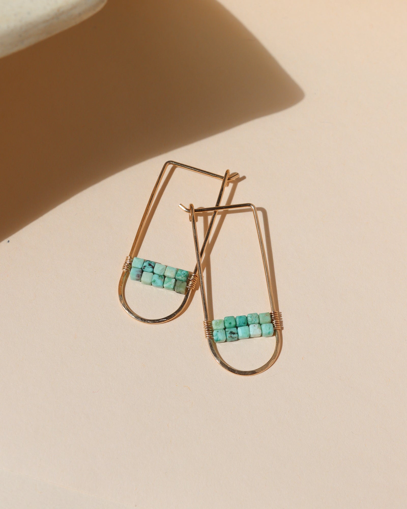 14k gold fill hoops with turquoise stones on a light dish