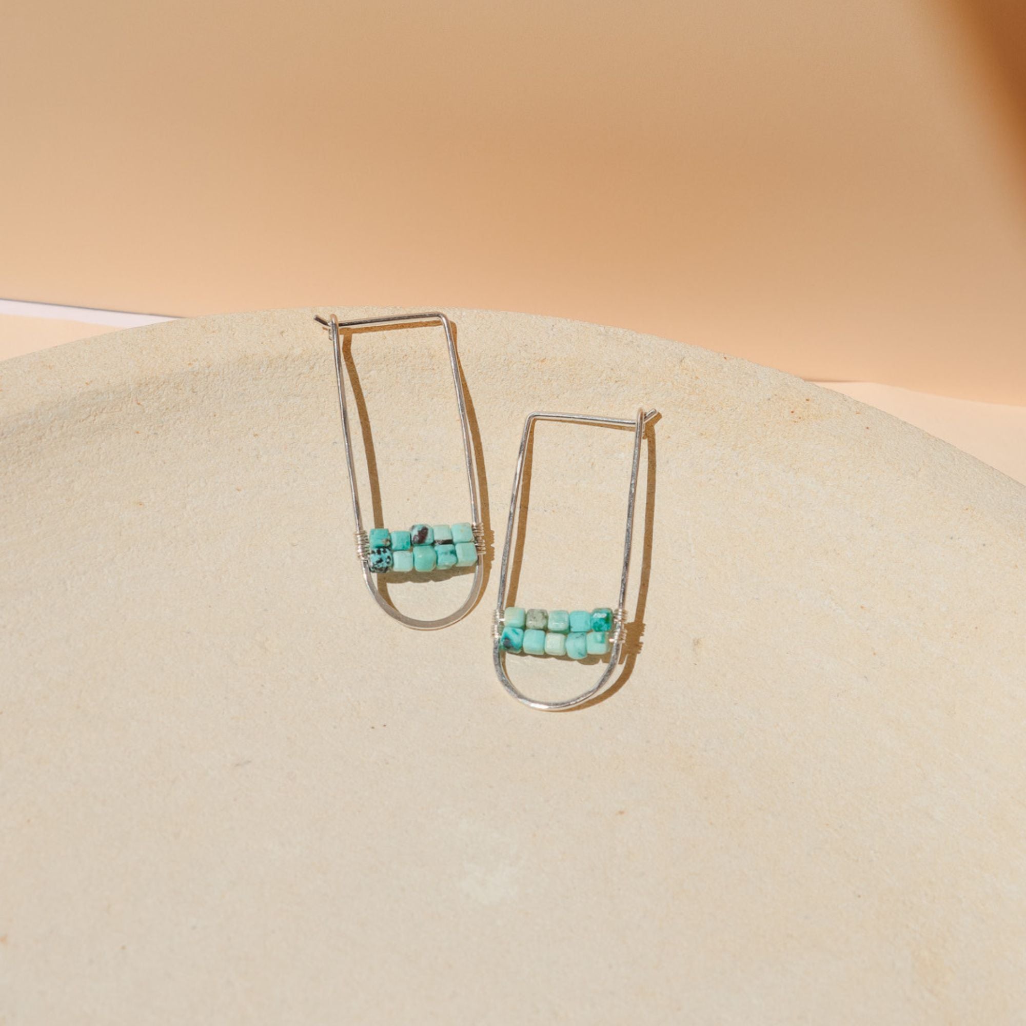 sterling silver hoops with turquoise stones on a light dish