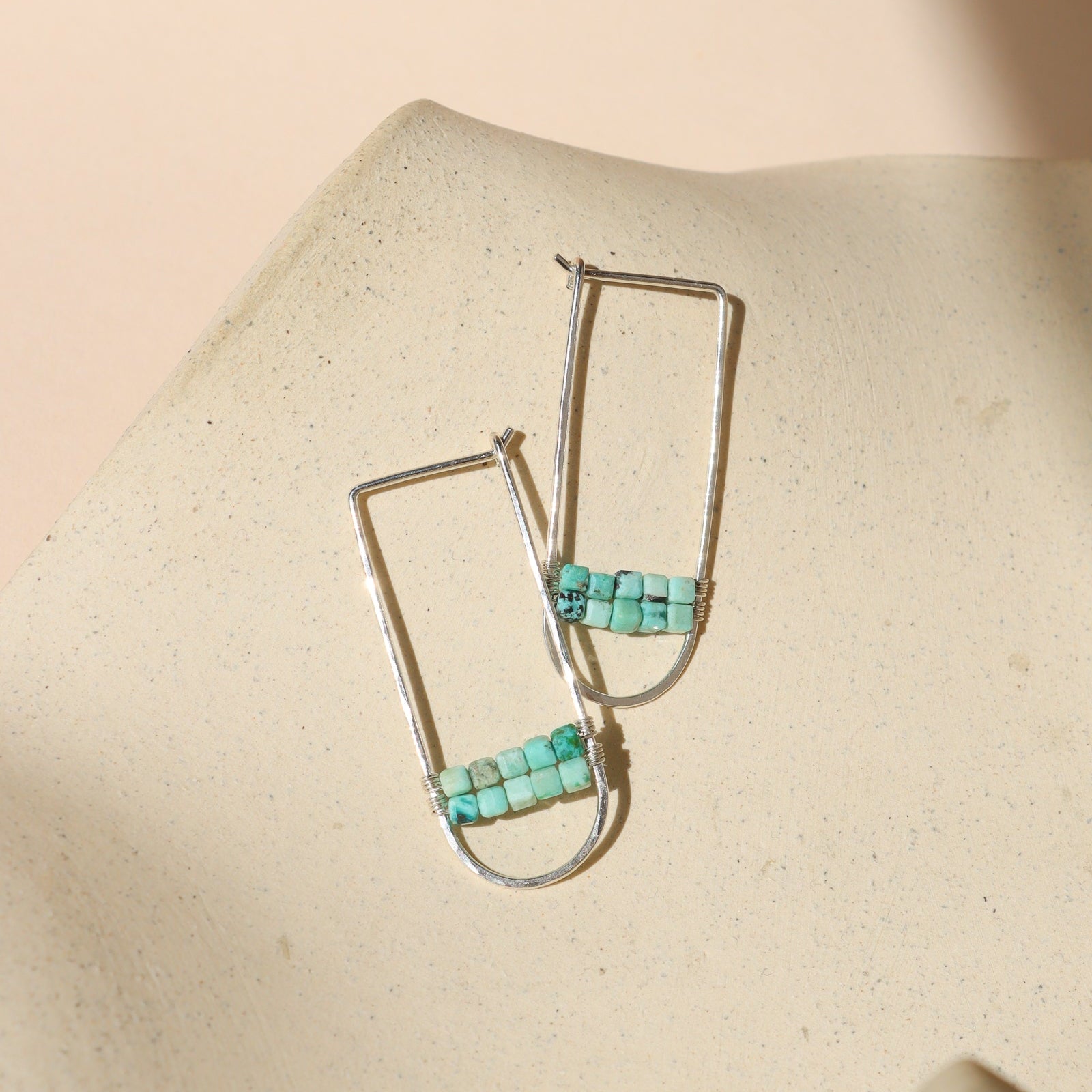 sterling silver hoops with turquoise stones on a light dish