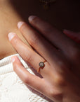 A woman wearing a ring band with a small 14k gold filled disc that's stamped with a birth flower.