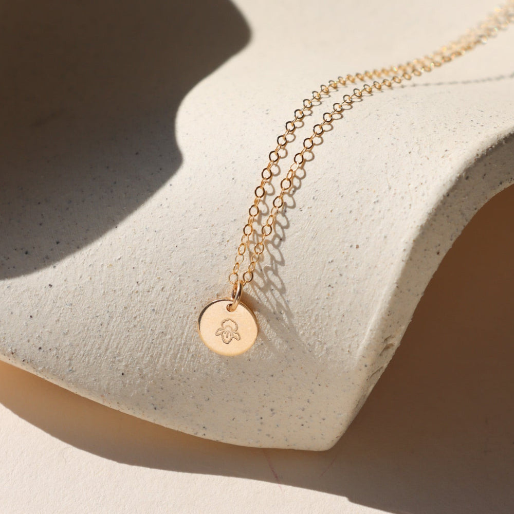 Birth flower necklace draped on a ceramic plate