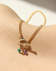 A simple 14k gold fill toggle featuring three tiny birthstone charms, dangling from a small toggle on a curb chain. The bracelet is displayed orange dish. 