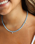 Model wearing a 14k gold fill fully beaded necklace featuring blue opal gemstones and 6 freshwater pearls.